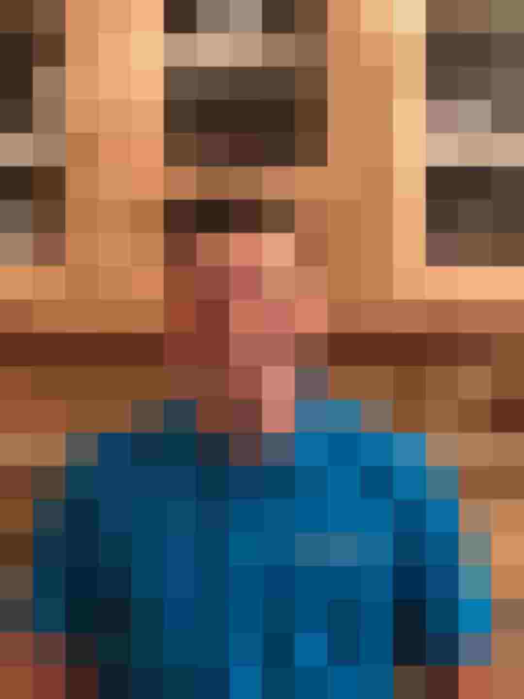 Mitarbeiter von Holzbau Gläser lächelt in blauer Arbeitskleidung vor Holzschrank.